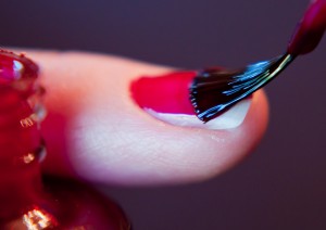 Red gel nail polish being brushed on nail